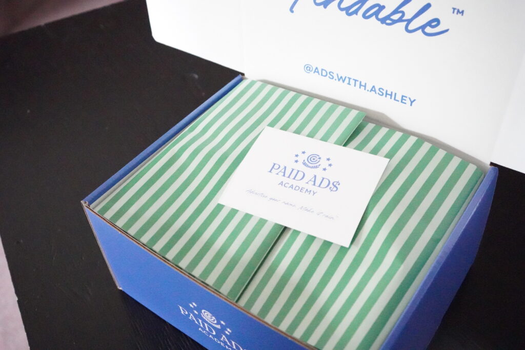 A branded onboarding gift box opened to reveal green-striped tissue paper and a welcome card on top