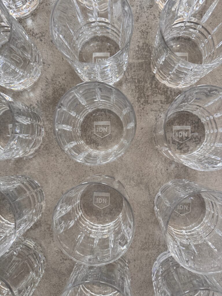 A set of cut-crystal glasses for professional gift boxes, each etched with a shield logo on the base