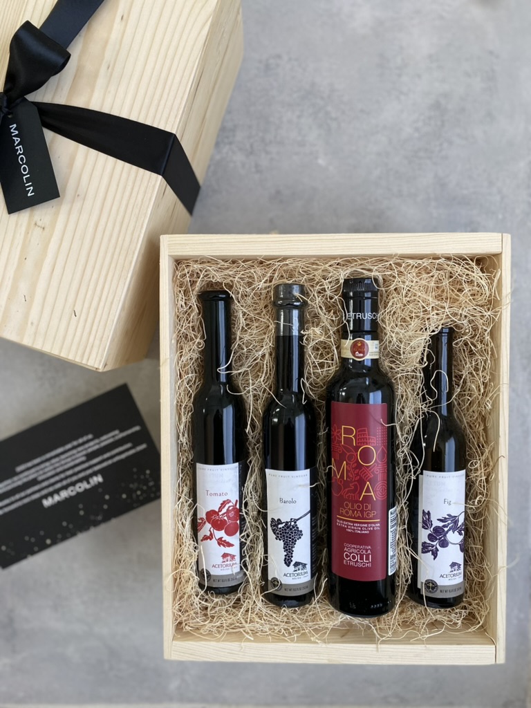 Corporate Christmas gift box with Italian olive oil and specialty vinegars nestled in wood wool, black ribbon and gift tag beside it