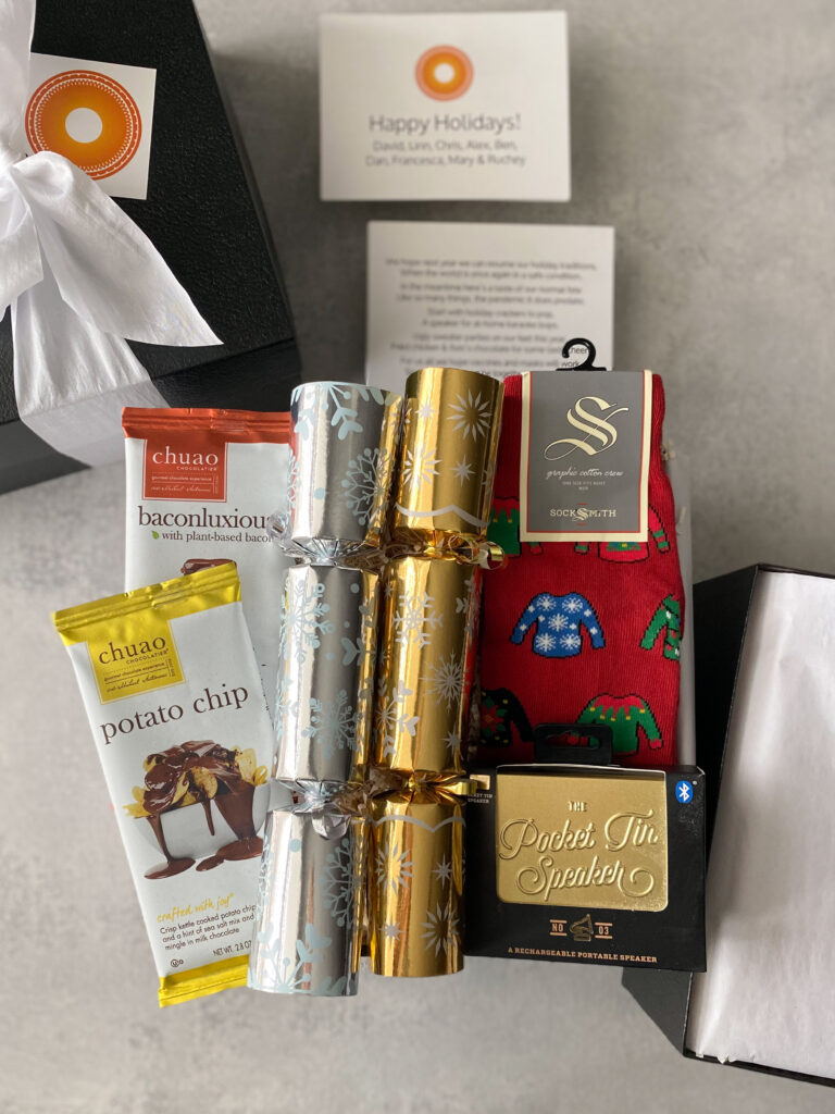 Corporate Christmas gift box with holiday crackers, novelty chocolate bars, ugly sweater socks, and a portable speaker