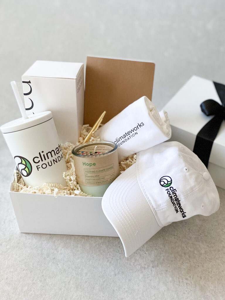 Employee onboarding gifts - branded ClimateWorks Foundation cap, tumbler, and welcome candle